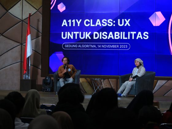 dua orang sedang duduk di hadapan para penonton. mc (kiri) memperkenalkan pembicara rahma. Di belakang mereka ada layar bertuliskan Accessibility atau alli class ux untuk disabilitas, egdung algoritma 14 November 2023